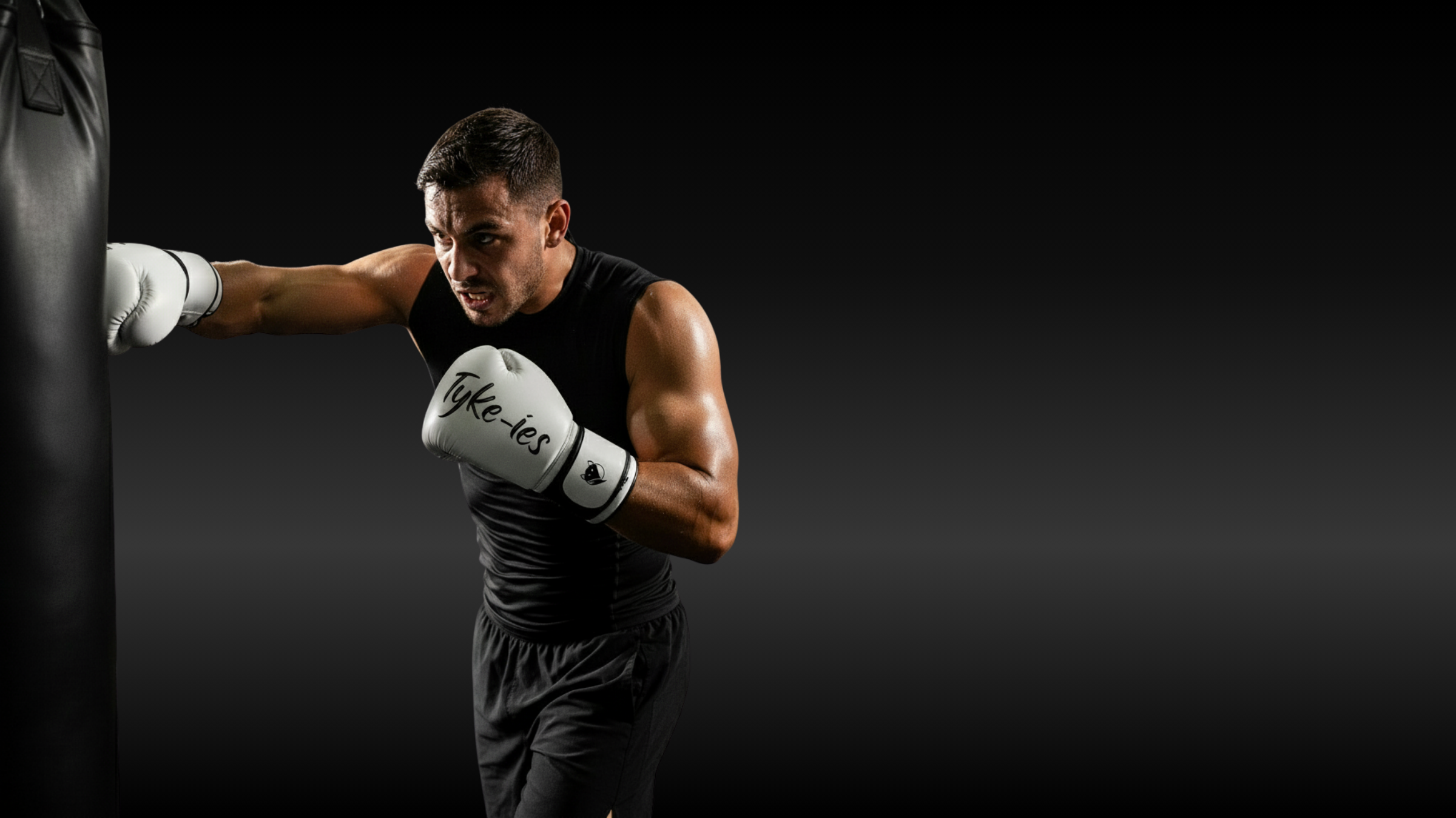 Fighter wearing Tyke-ies professional boxing gloves hitting a heavy bag in a gym setting.